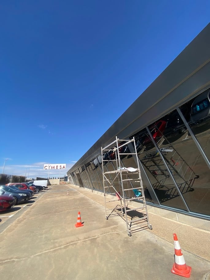 Construction site with metal scaffolding in front of a large industrial building under renovation on a clear sunny day